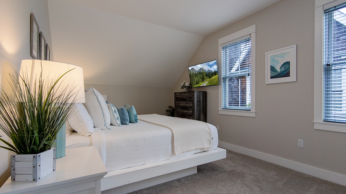 The guest bedroom has a wall-mounted TV