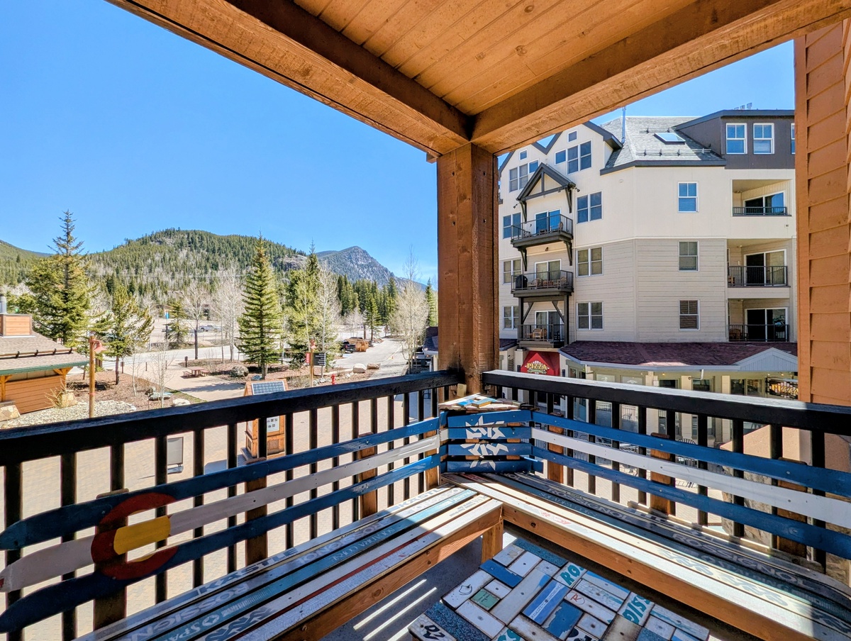 Private balcony overlooking a mountain landscape and nearby buildings, framed by warm wooden beams that invites relaxation in the fresh alpine air. #Spring
