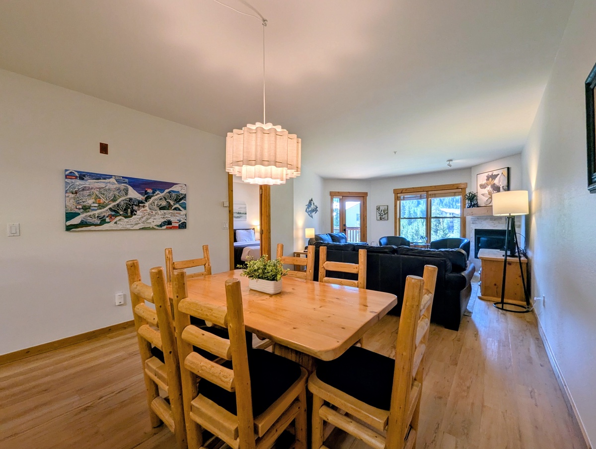 Gather around the rustic wooden table under soft, elegant lighting as your group plans tomorrow's adventures, with the cozy living room just steps away inviting you to relax afterward.