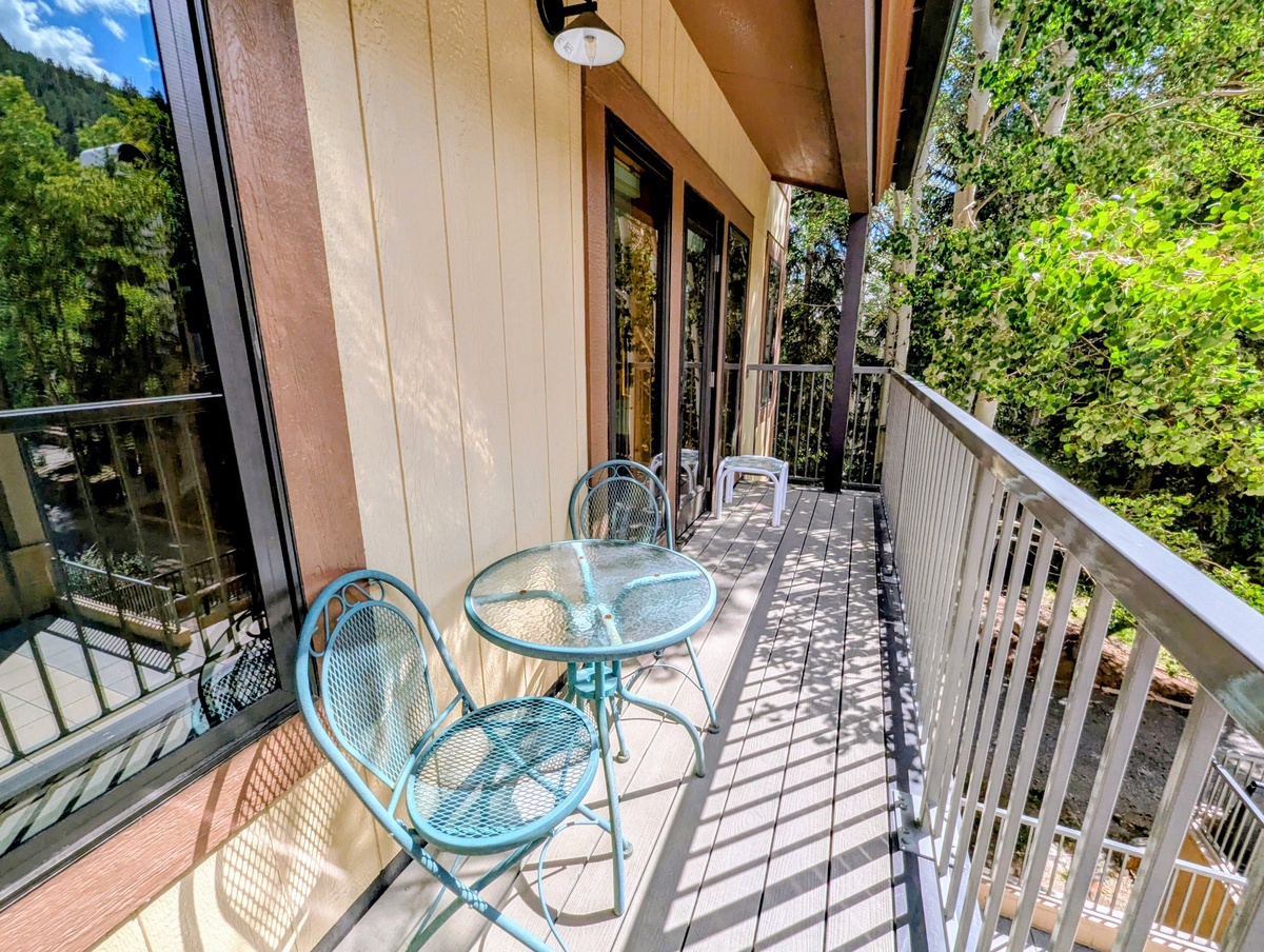 Step onto your private covered balcony with a cozy bistro set where you'll enjoy morning coffee surrounded by lush trees and peaceful mountain scenery—your perfect spot to unwind.