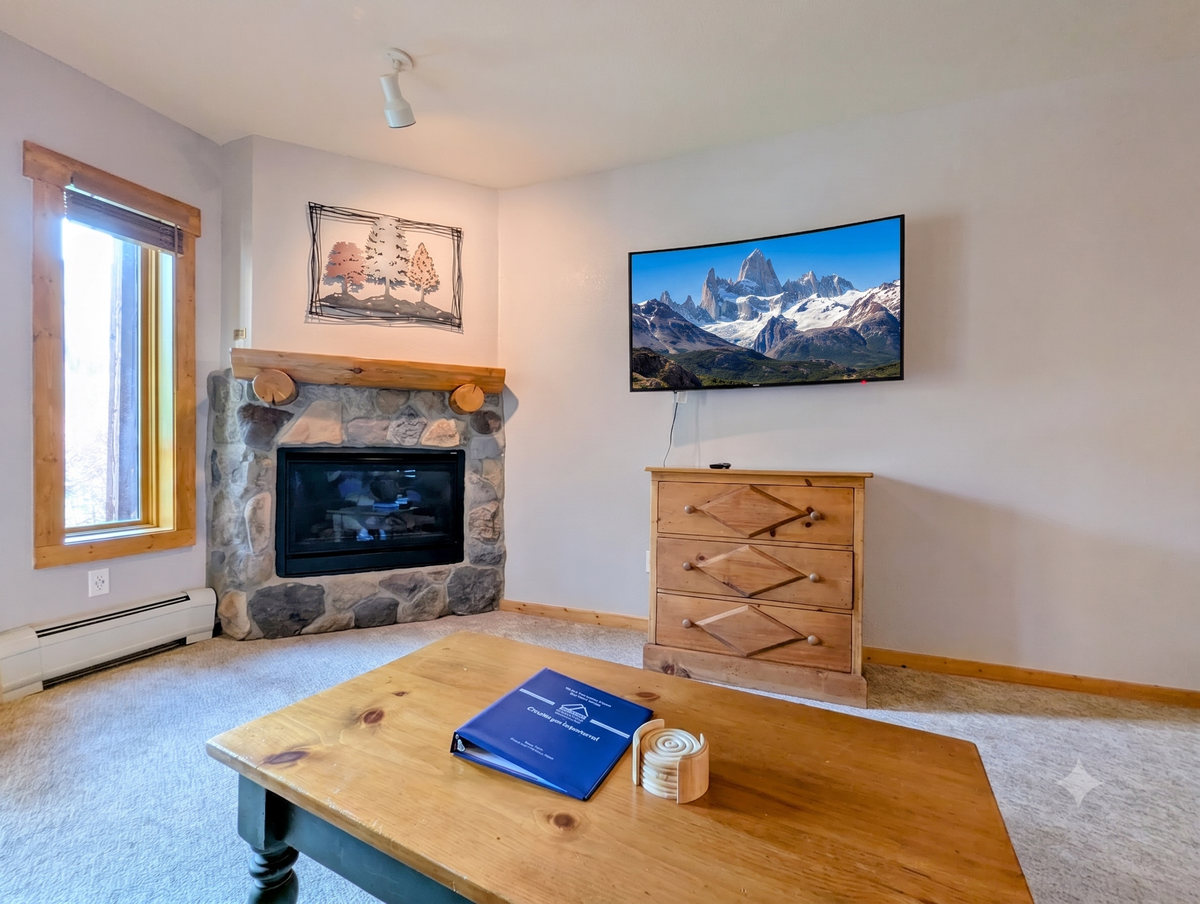 Unwind in your cozy living space where a stone fireplace adds warmth and rustic charm. Natural light streams in, and you can curl up by the fire after a day exploring the mountains.