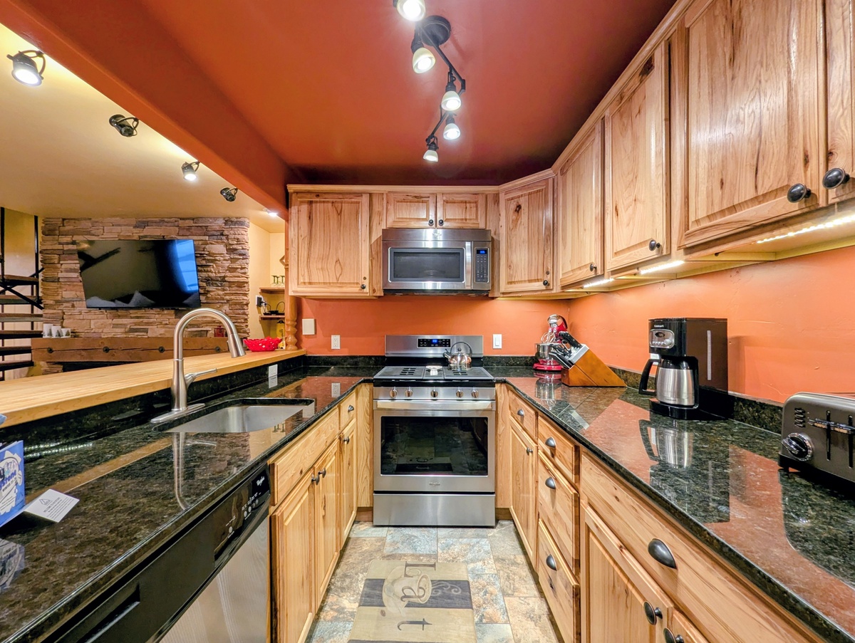 Whip up your favorite meals in this fully-equipped kitchen featuring warm wood cabinets, granite counters, and modern appliances.
