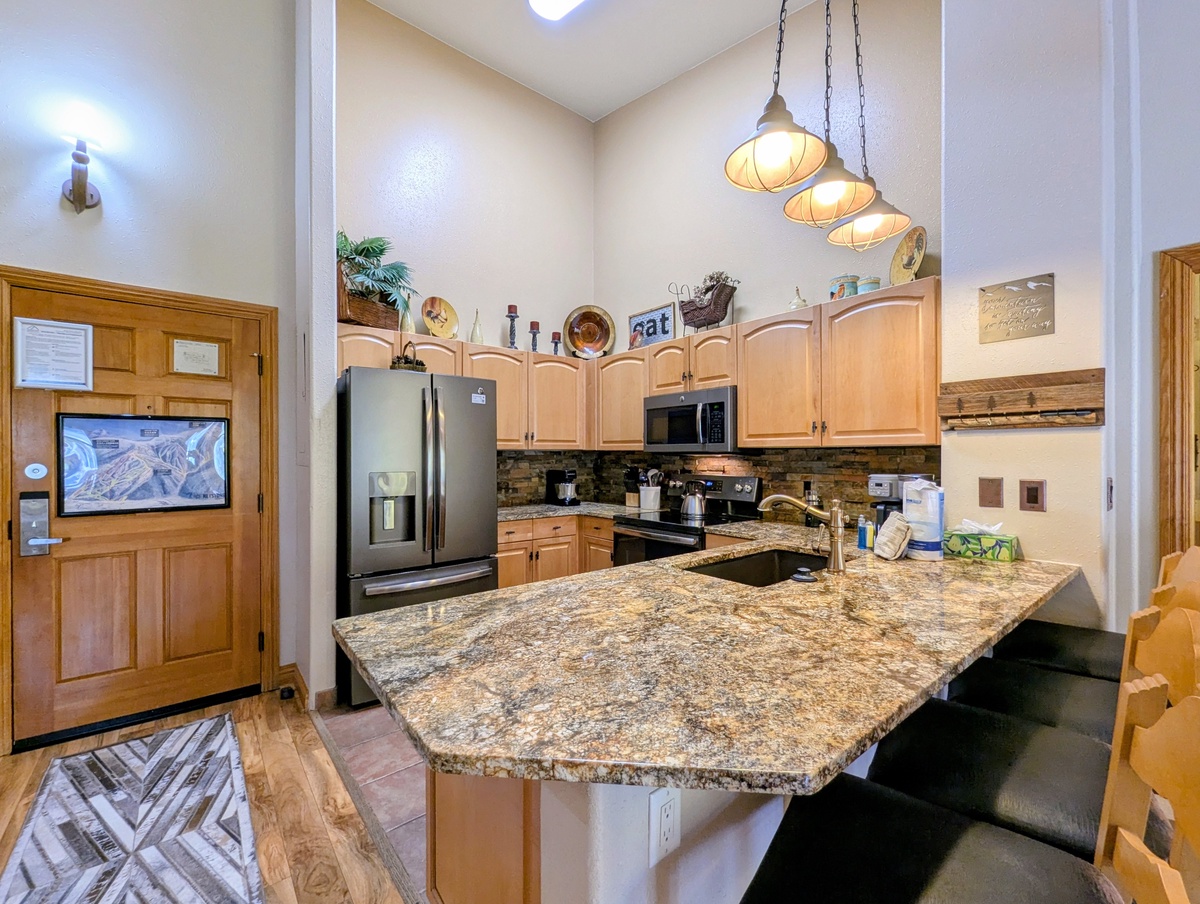 Your fully-equipped mountain kitchen awaits, with granite countertops, modern appliances, and charming pendant lights creating the perfect spot to gather and prepare meals together.
