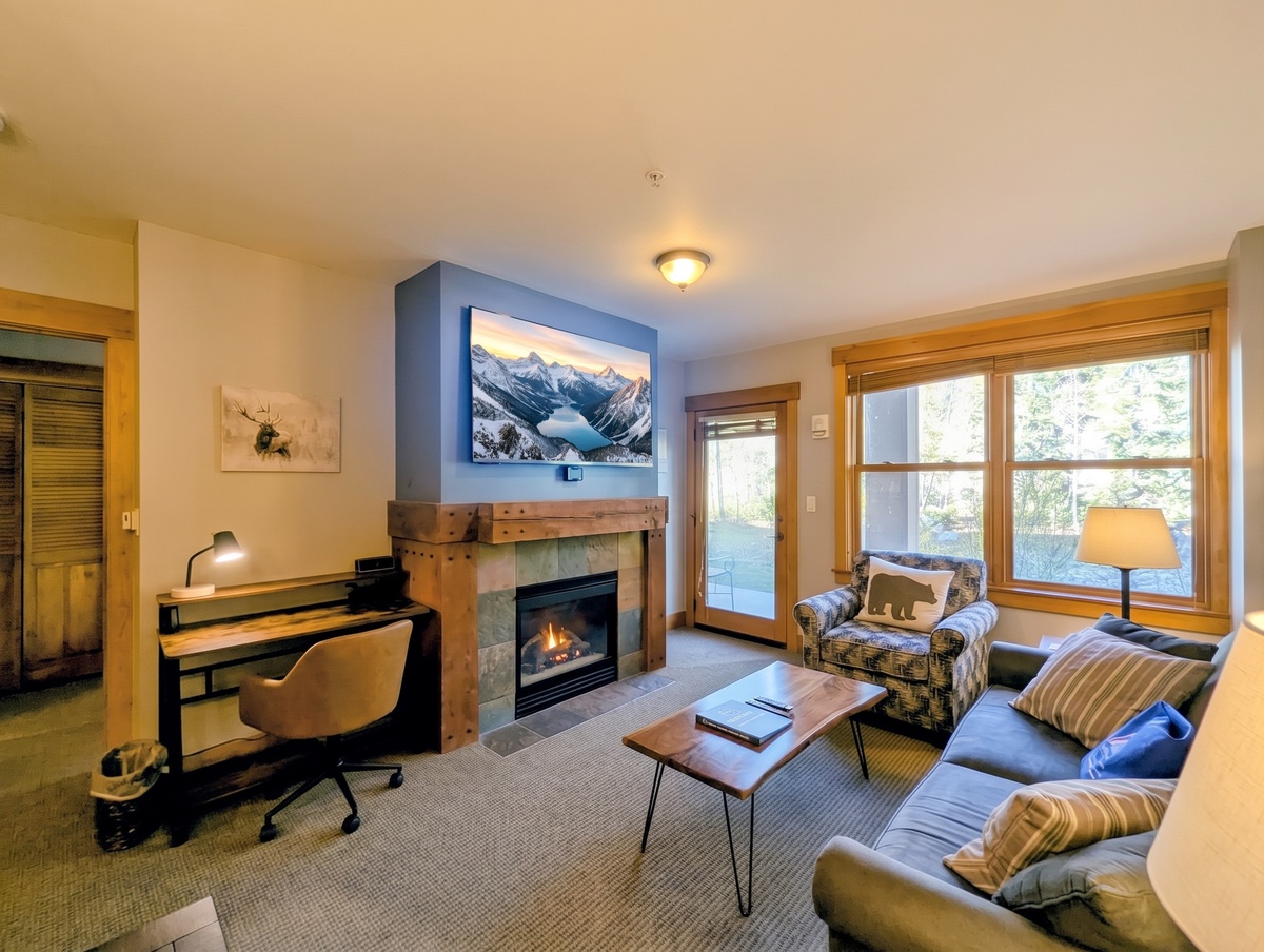 Sink into the inviting sofa by your glowing fireplace, where warm wood tones and mountain-inspired décor create a cozy retreat after a day of adventure.
