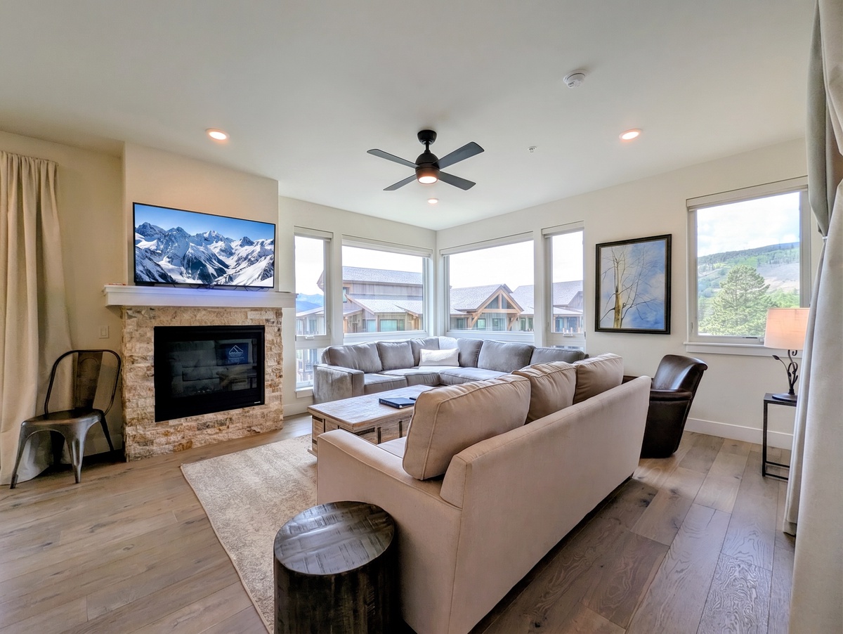 Sink into plush sofas and let your gaze wander through expansive windows to rolling green hills, while the cozy fireplace and modern comforts wrap you in relaxation.