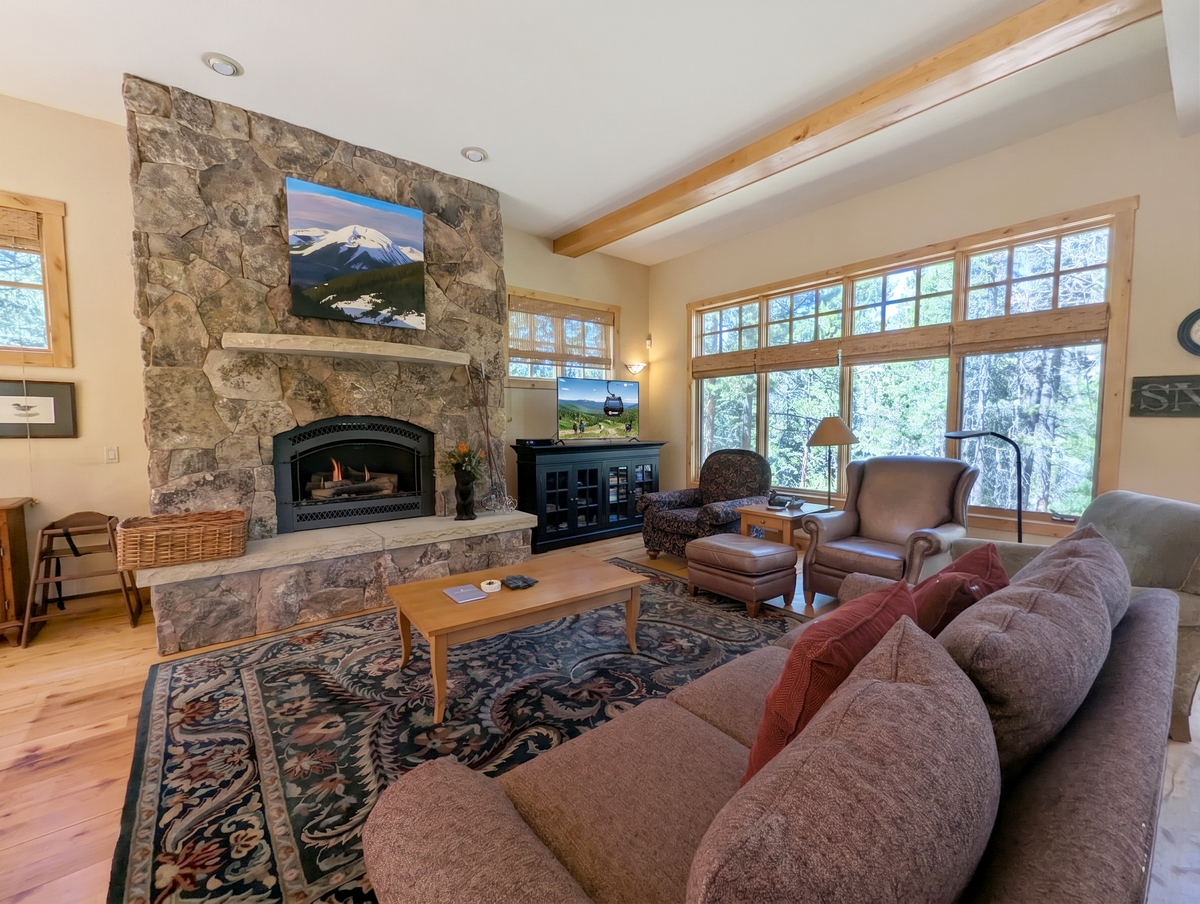 Unwind in your spacious living room where a stone fireplace warms cozy evenings and large windows frame stunning forest views.