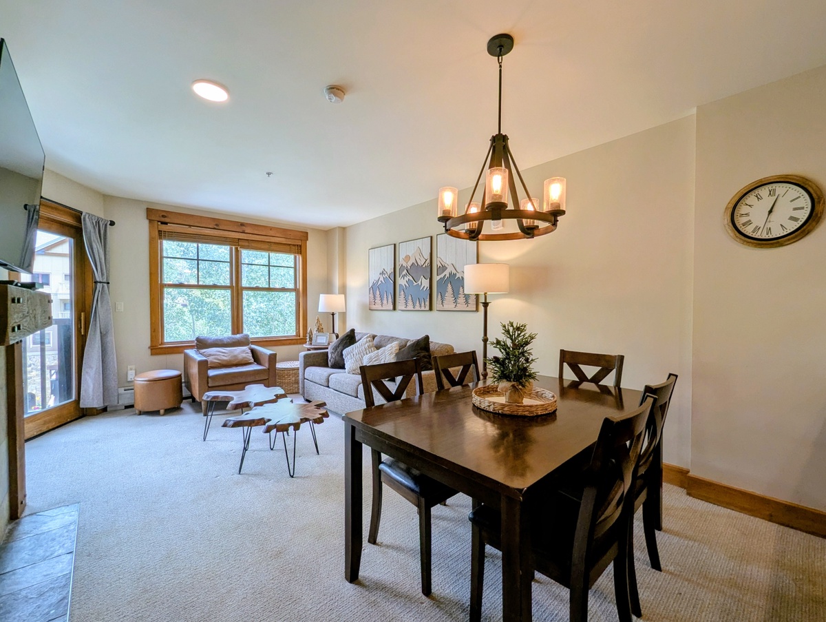 Open-concept living area where natural light, rustic mountain charm, and modern comfort blend perfectly. Gather around the dining table or unwind on the cozy sofa in this thoughtfully designed retreat.