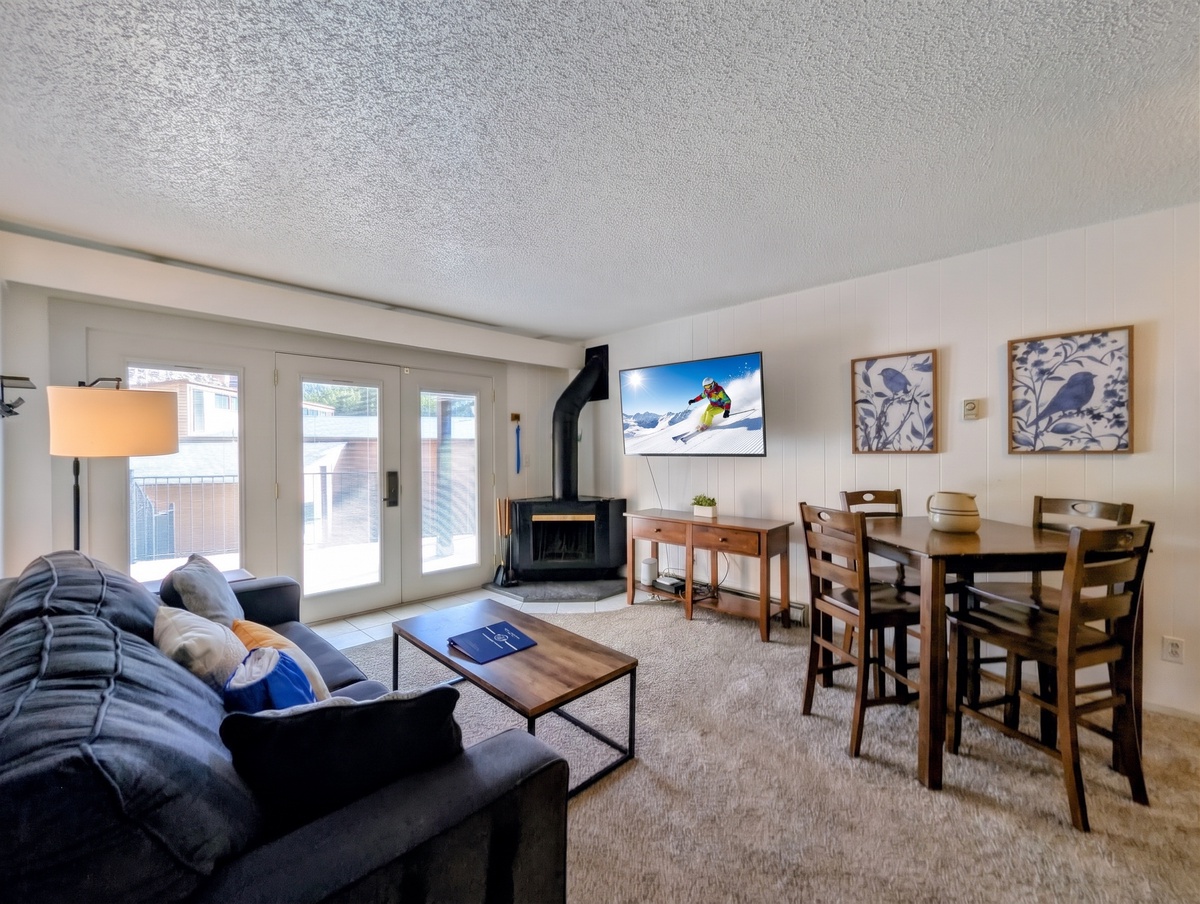 Relax in your cozy living space with a warm fireplace, comfortable seating, and plenty of natural light streaming through the patio doors.