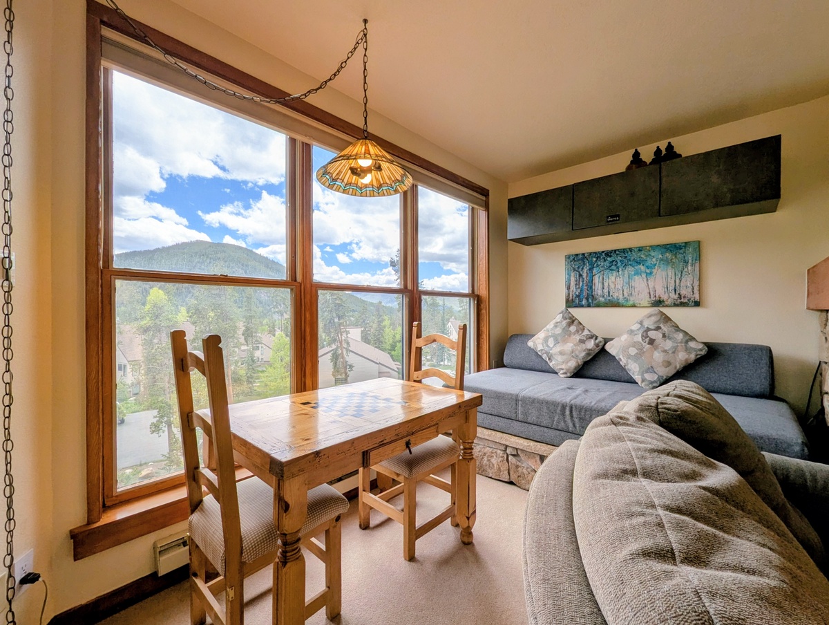 Unwind in your cozy living space with stunning mountain views, where rustic wooden accents and soft seating invite you to relax and soak in the natural beauty through expansive windows.