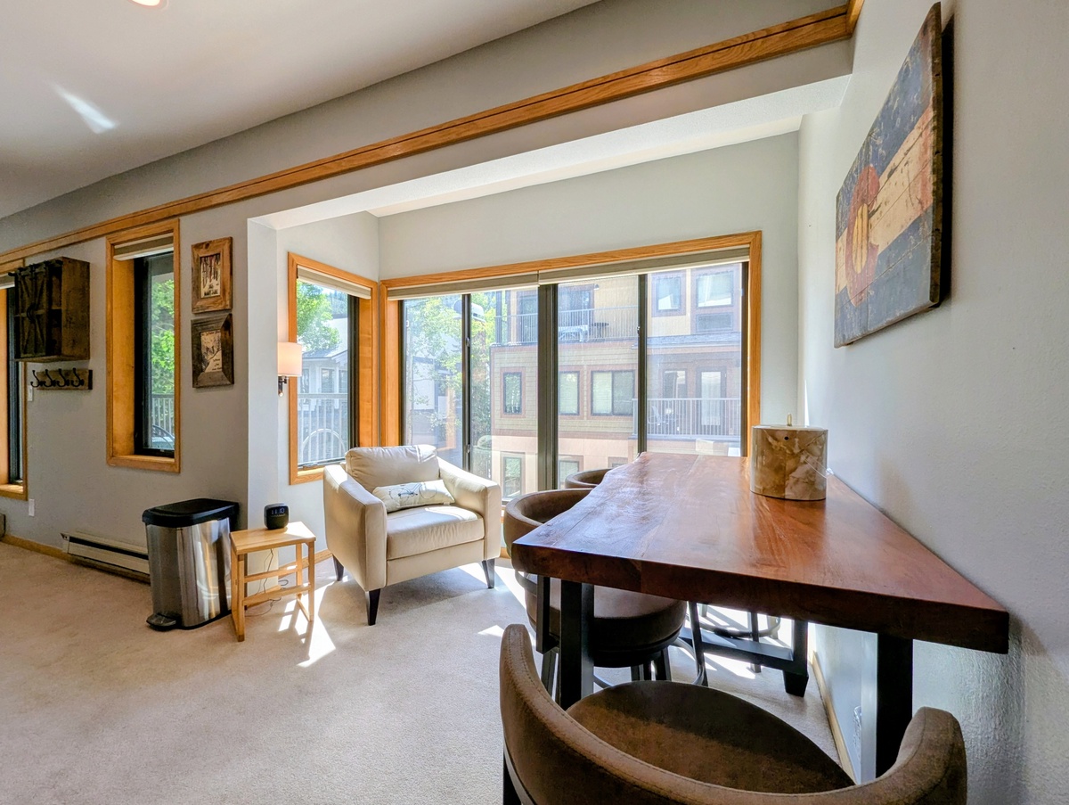 Settle into your light-filled retreat where warm wood tones meet modern comfort. Sip morning coffee at the handcrafted dining table, or curl up in the plush armchair and soak in natural light streaming through large windows.