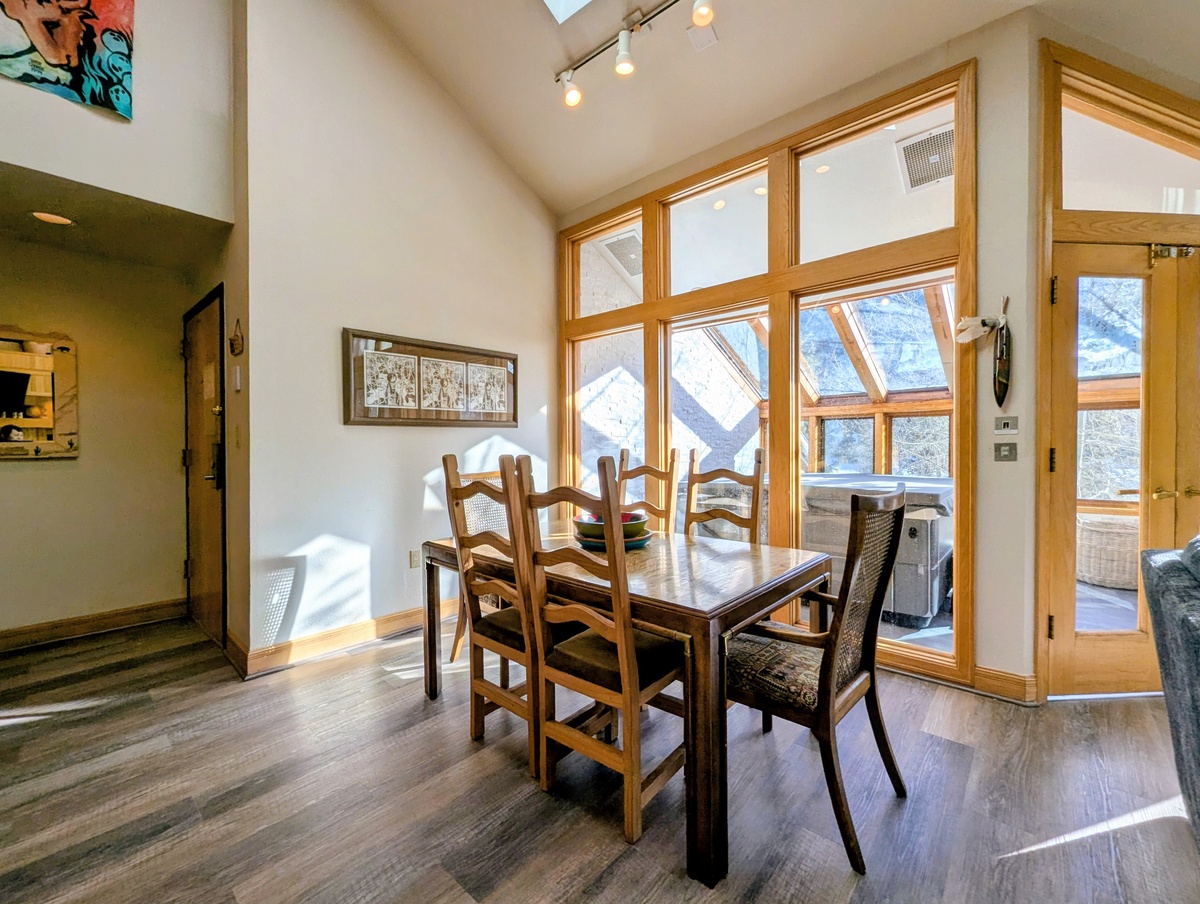 Gather around your dining table where warm wood tones and soaring windows frame stunning mountain views for memorable meals together.