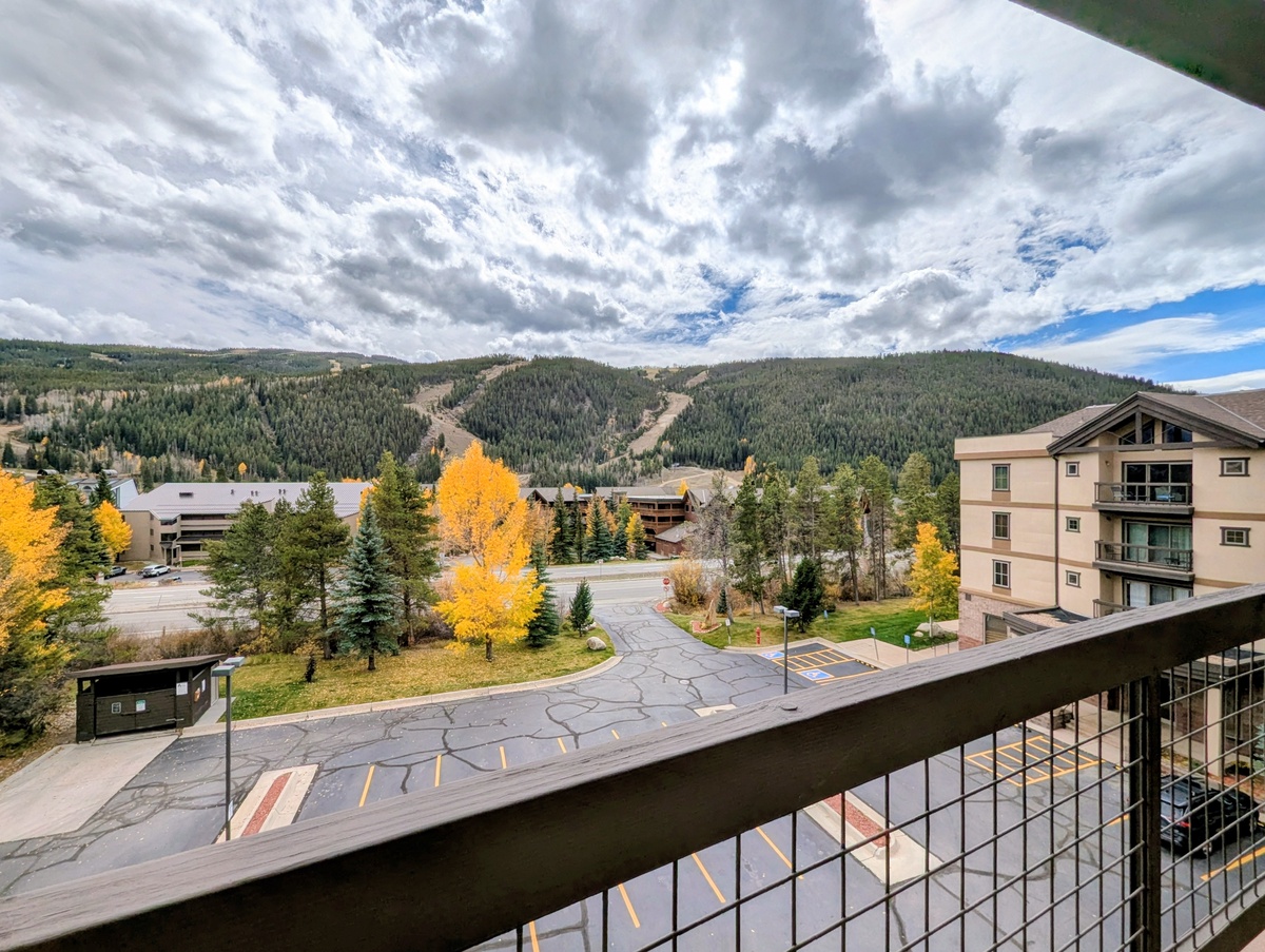Mountain resort views with autumn colors and ski slopes stretching toward forested peaks under dramatic skies.