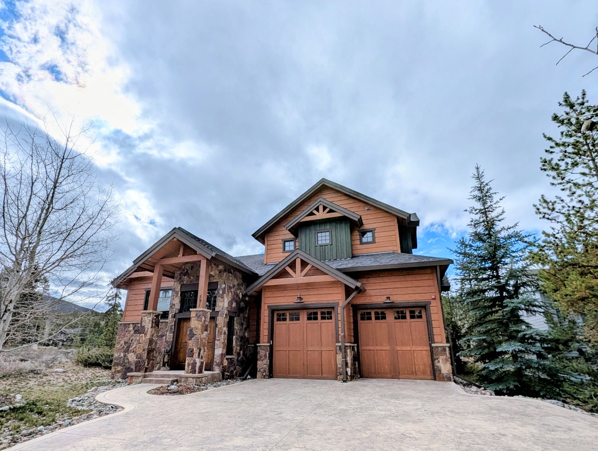 Charming mountain retreat featuring warm wood siding, rustic stonework, and a welcoming covered entry, nestled among evergreens in a peaceful alpine neighborhood.