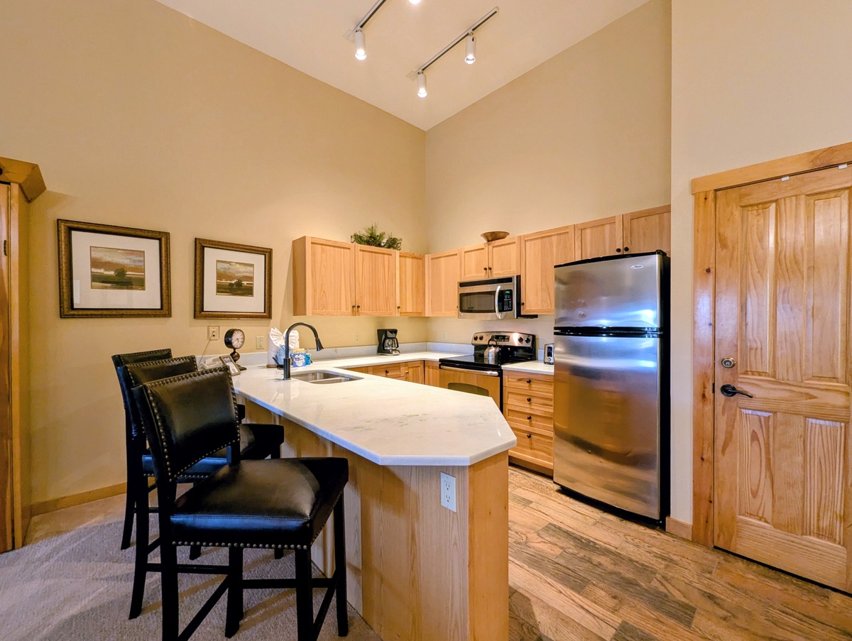 Your fully equipped kitchen features stainless appliances, warm wood cabinetry, and a breakfast bar with seating—perfect for preparing meals and gathering with friends or family.