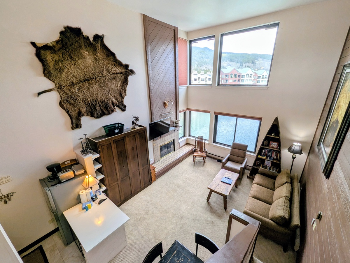 Cozy up in your spacious living room with rustic charm, featuring a stone fireplace and stunning mountain views through expansive windows.