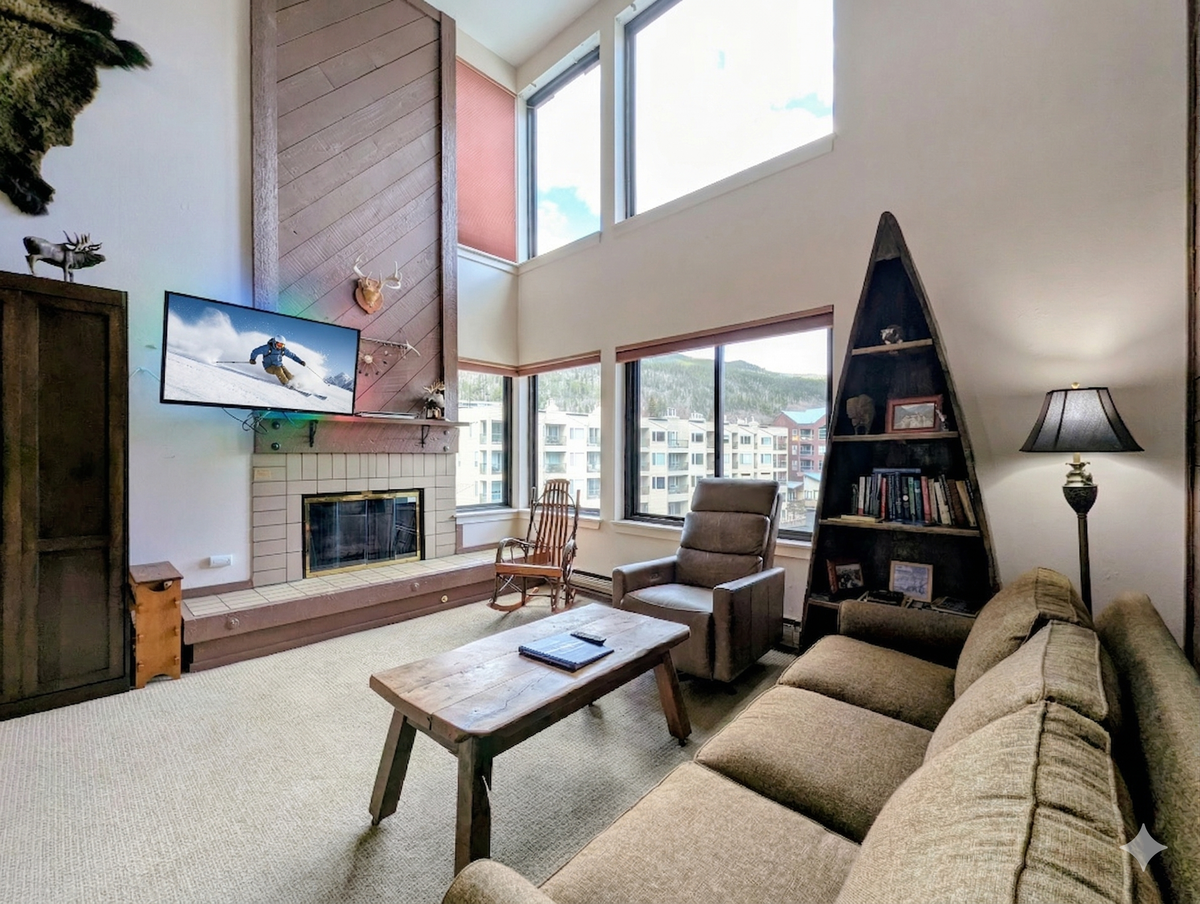 Unwind in your spacious living room featuring a cozy fireplace, mountain views, and unique canoe bookshelf for memorable evenings.