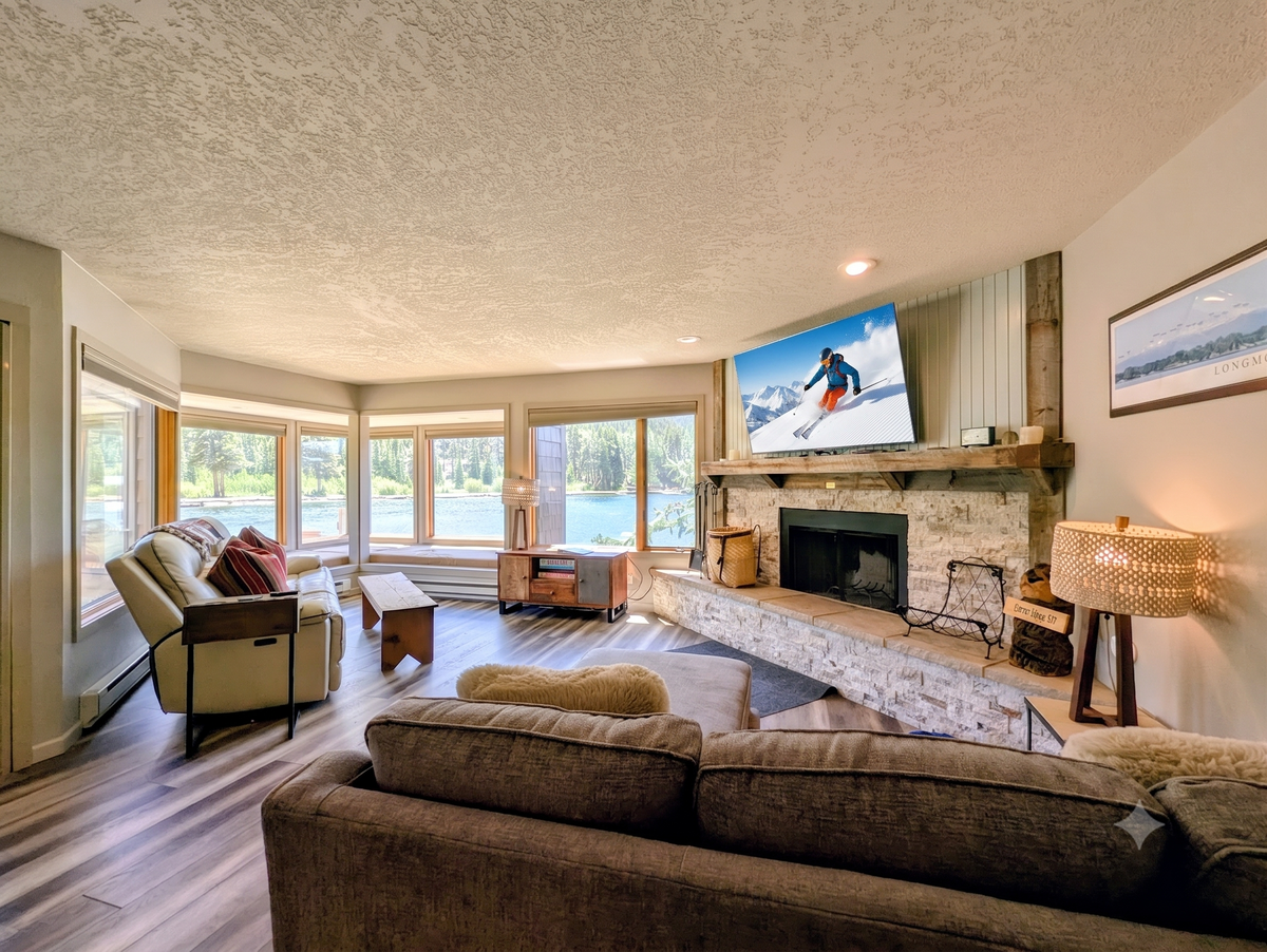 Sink into plush sofas by the stone fireplace, watch the lake shimmer through panoramic windows, and unwind in your cozy, sunlit retreat—perfect for every season.