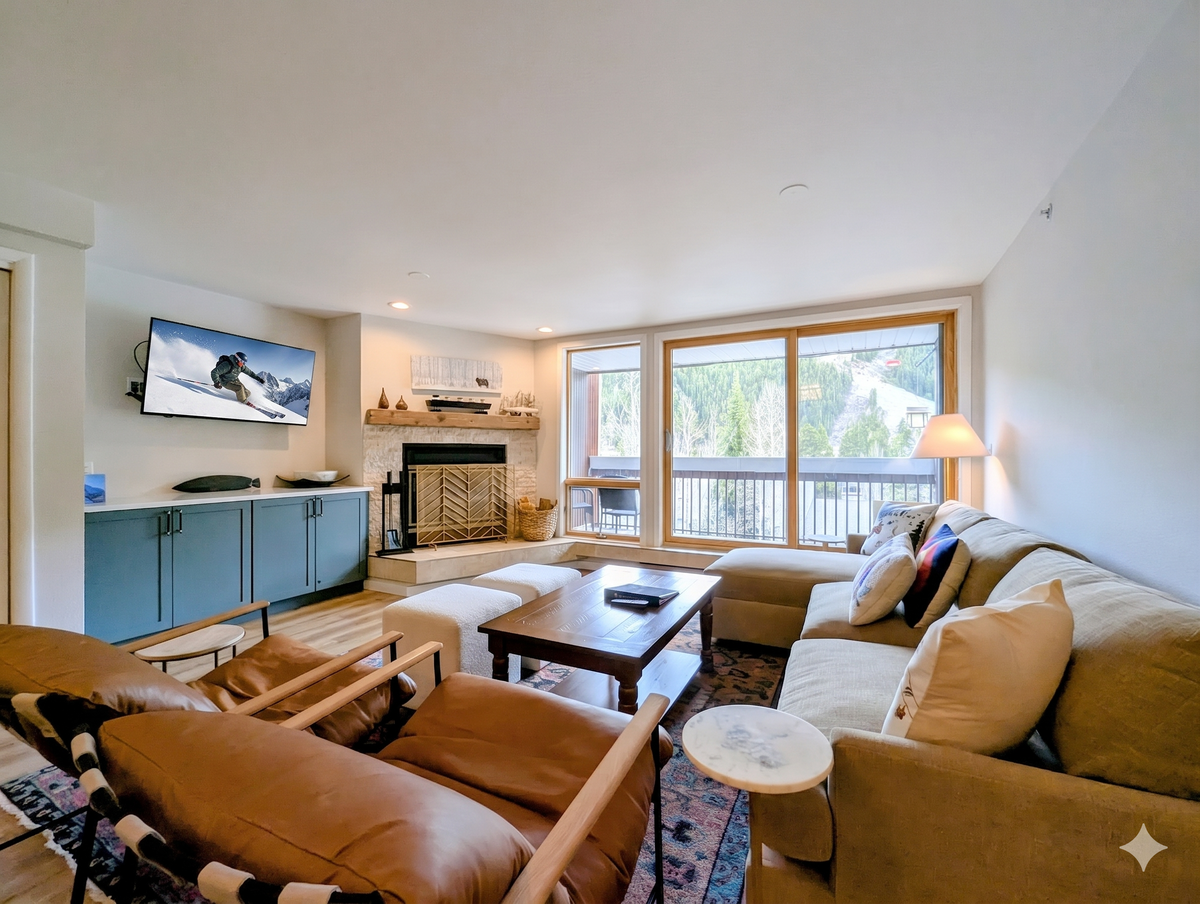 Unwind in your cozy living room, where plush seating surrounds a stone fireplace and mountain views frame your alpine escape through bright windows.