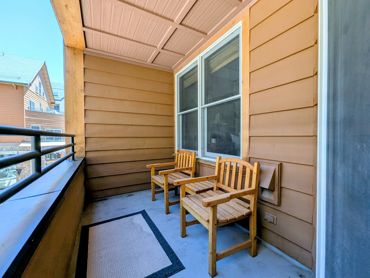 Step out onto your private covered balcony, where two inviting wooden chairs await your morning coffee or evening unwind. The cozy space offers a perfect retreat to relax and breathe in the fresh air.