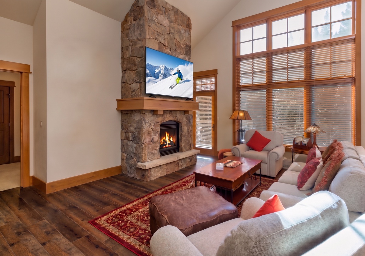 Sink into plush seating while the crackling fireplace warms your mountain retreat. High ceilings and abundant natural light create an airy gathering space where you'll unwind after your alpine adventures.