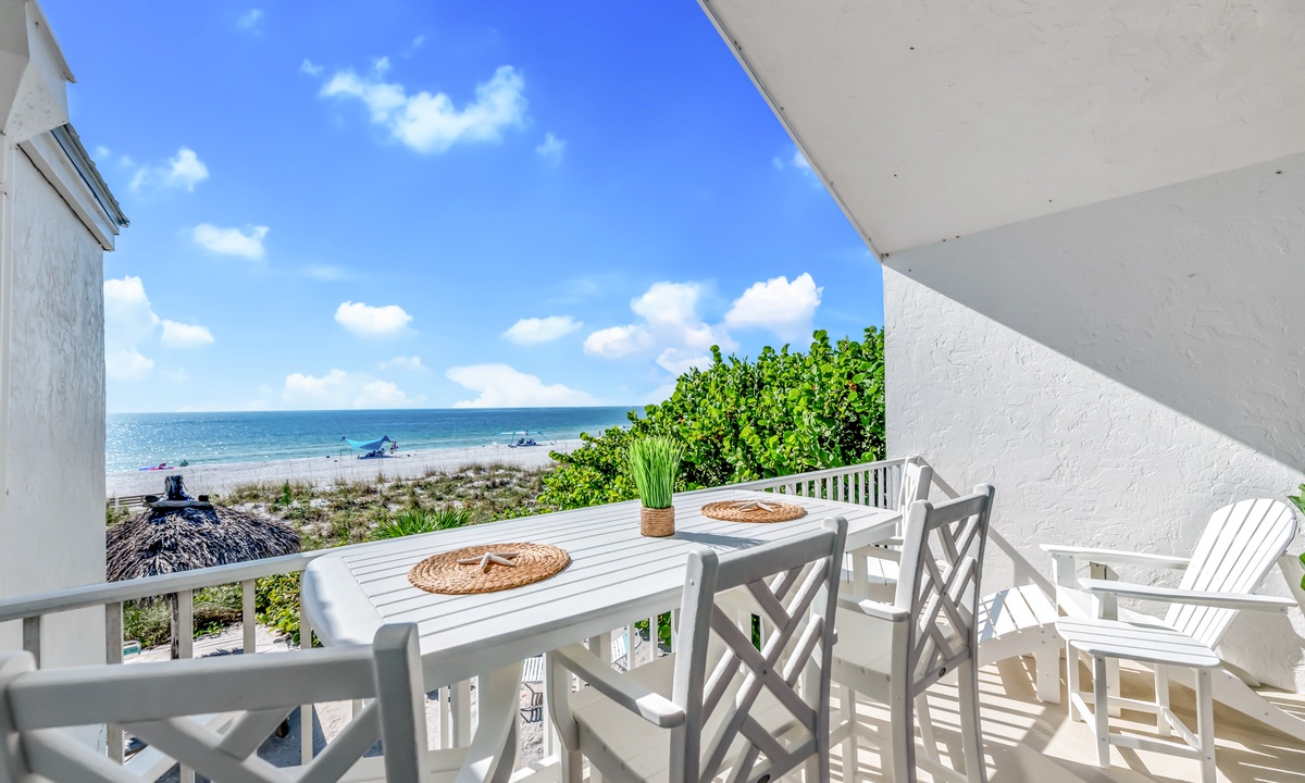 a table and chairs on a balcony overlooking a beach on Anna Maria Island