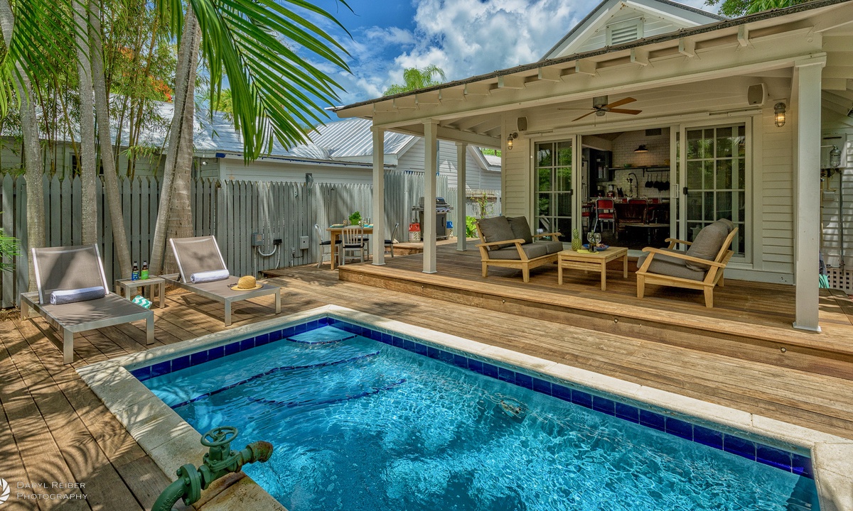 Backyard photo of a vacation home in Last Key Florida. The house has doors that open to the backyard that includes a pool.