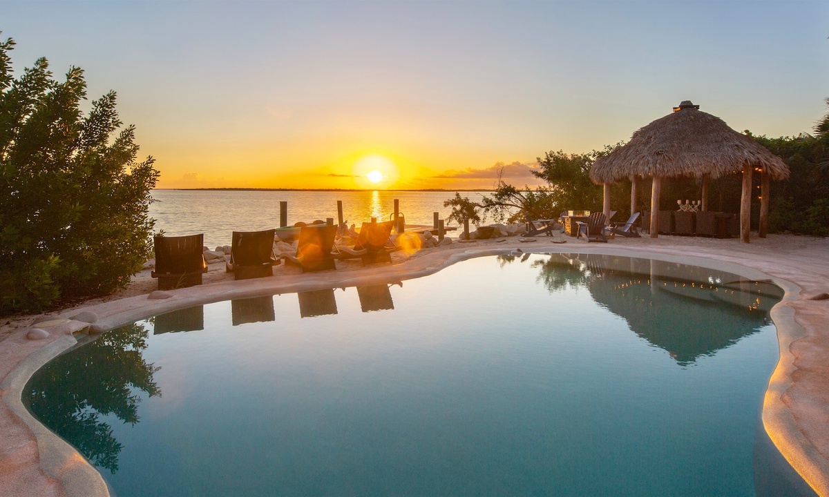 A pool with chairs and a hut on the side at a vacation rental in Key West Florida.