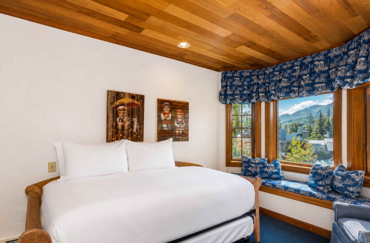 Sink into crisp white linens beneath a warm wood ceiling, while mountain and forest views through your window seat frame the perfect alpine escape.