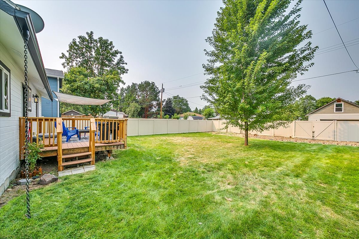 Spacious fenced backyard with mature trees and wooden deck - perfect for morning coffee or evening relaxation in your private outdoor haven.