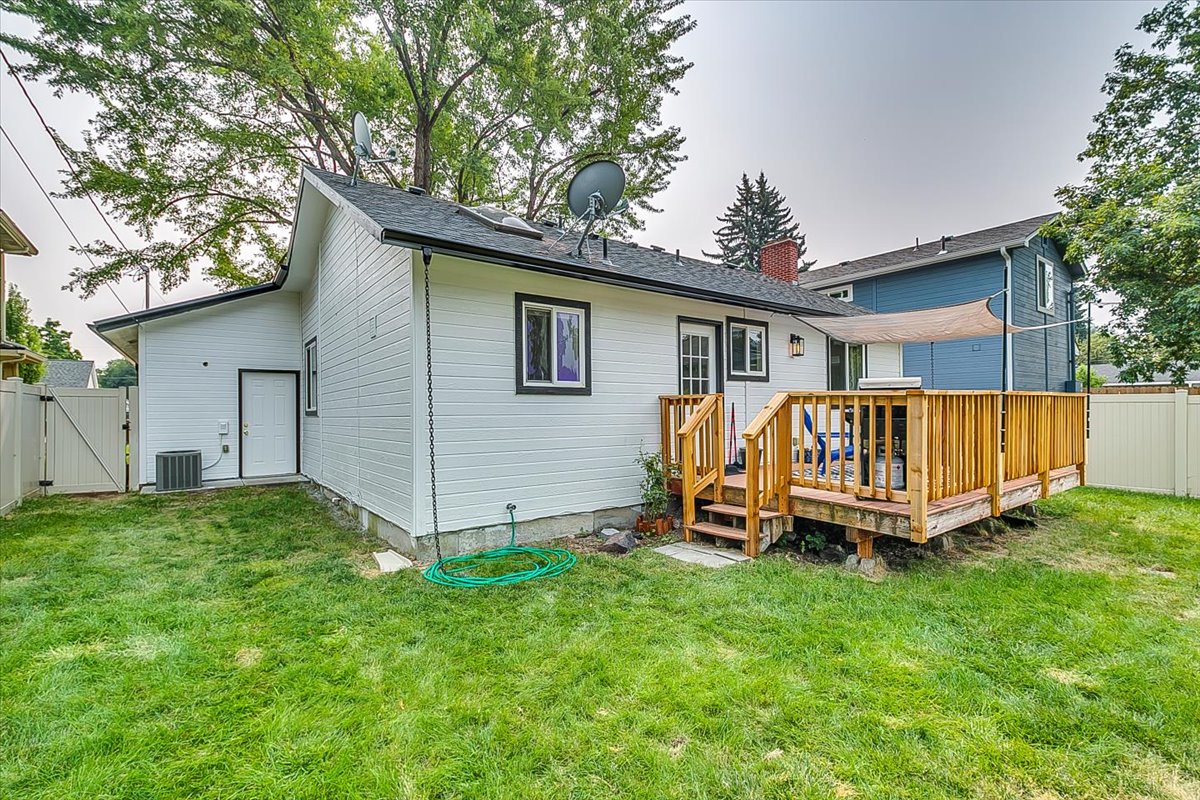 Charming white cottage with wooden deck and spacious yard in quiet residential neighborhood.
