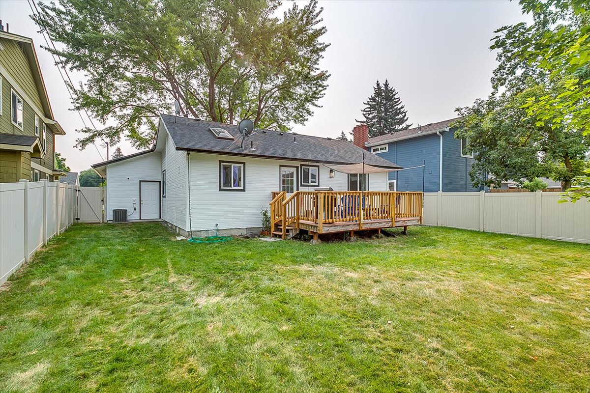 Spacious backyard with wooden deck surrounded by mature trees in quiet residential neighborhood.
