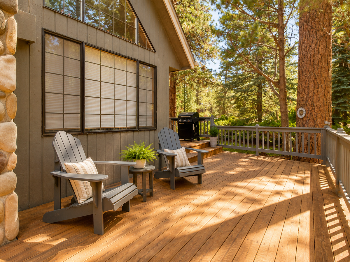 Sunlit deck with cozy Adirondack chairs and BBQ, where your mornings start with coffee among towering pines and peaceful forest views.