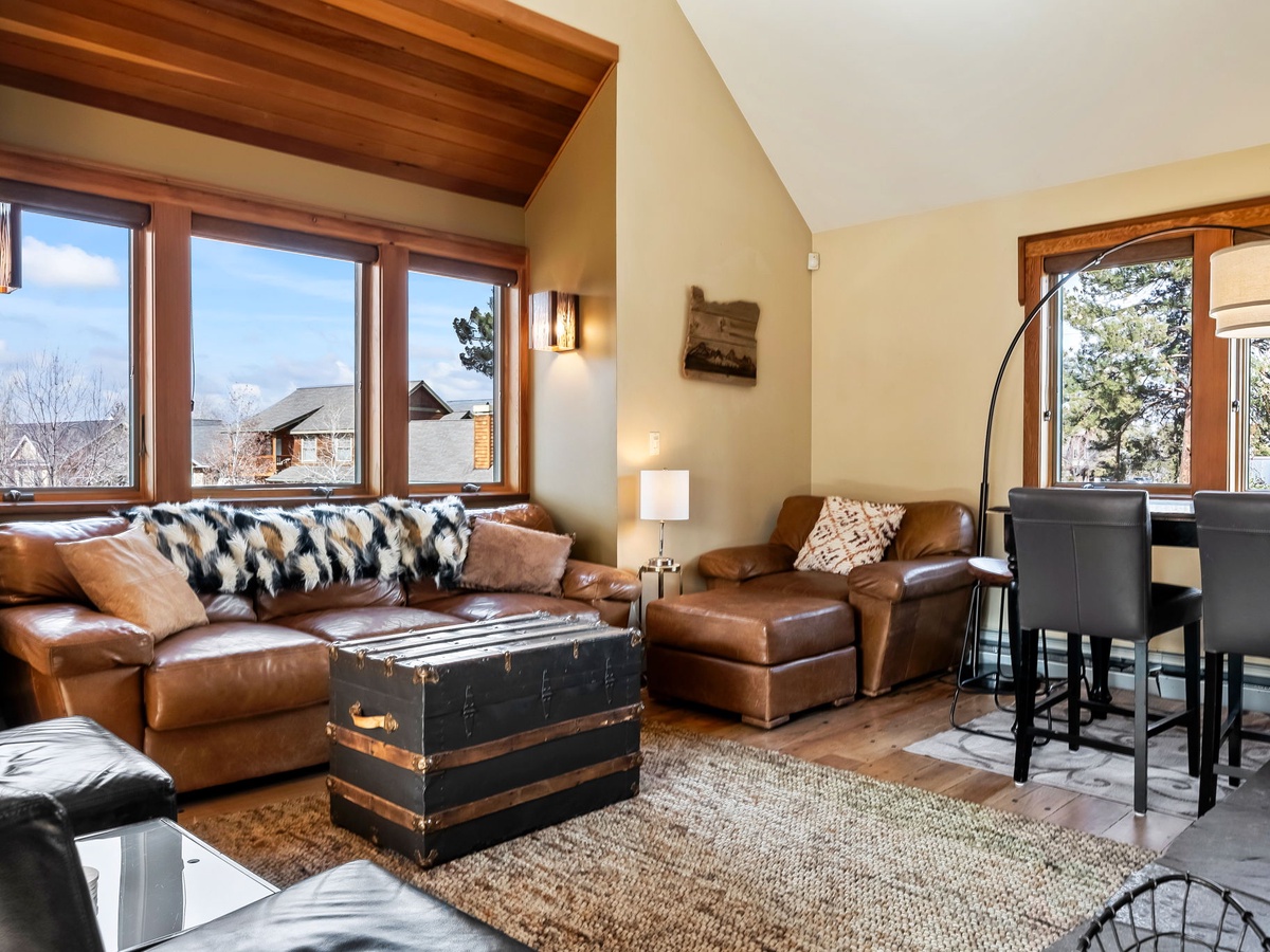 Unwind on plush leather seating in your bright, vaulted living space, where warm wood beams and mountain views invite relaxation and cozy conversation.