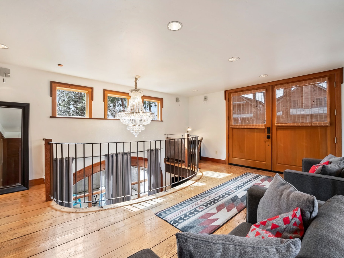Relax on plush sofas in your upstairs lounge, where warm wood tones, elegant lighting, and natural light through picture windows create an inviting retreat above the main living areas.