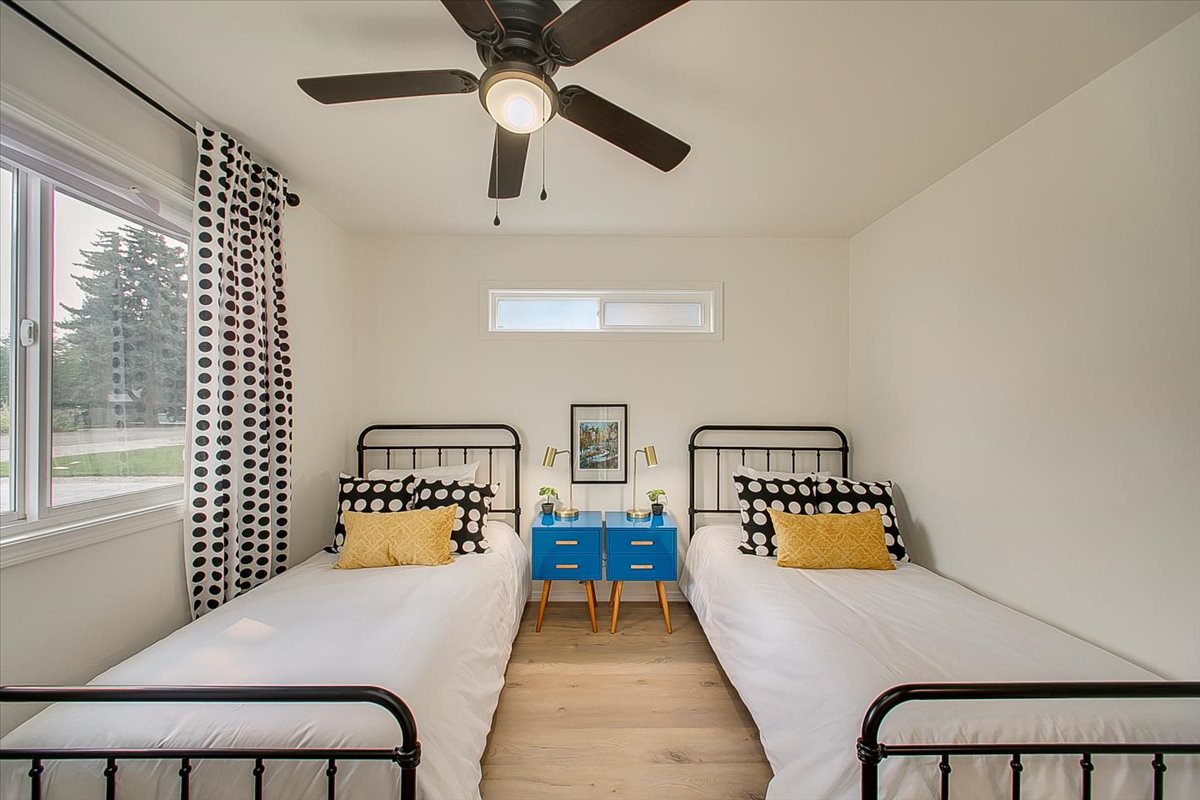 Your modern twin bedroom features crisp linens, playful polka dot accents, and a refreshing ceiling fan for comfortable nights.