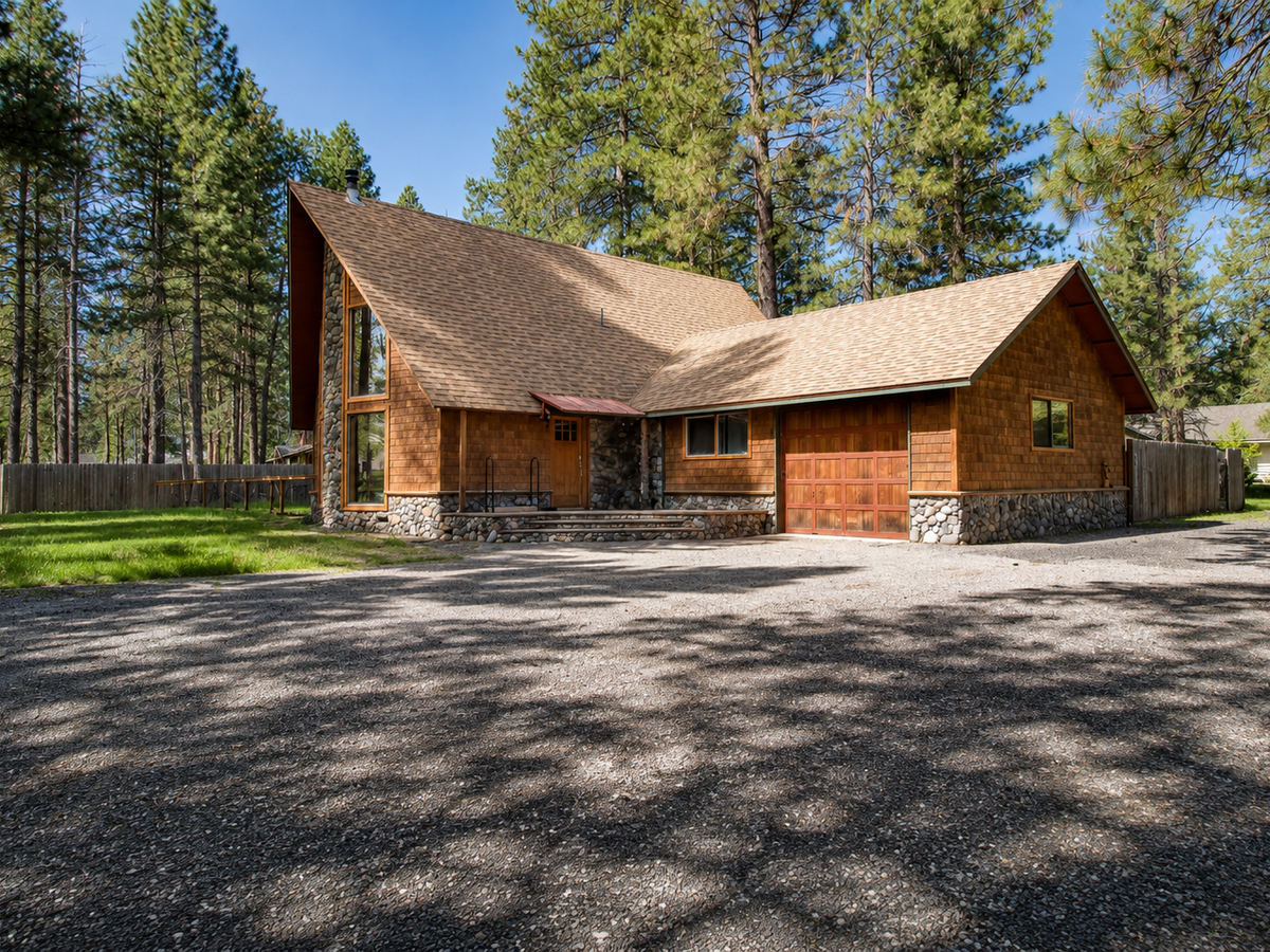 A welcoming cedar-shingled mountain retreat nestled among towering pines, featuring stone accents and a spacious driveway with ample parking for your stay.