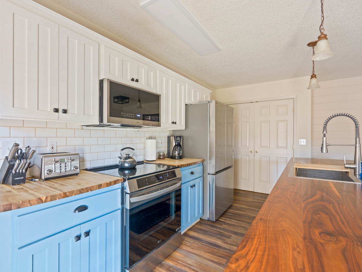 Your charming kitchen features butcher block counters, stainless appliances, and cheerful blue accents - perfect for preparing meals together.