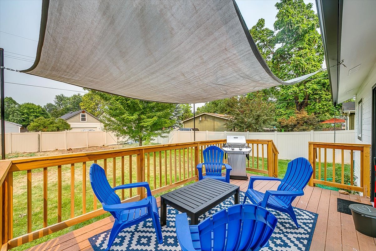 Unwind on your private deck with comfortable seating, BBQ grill, and shaded canopy overlooking the peaceful backyard.
