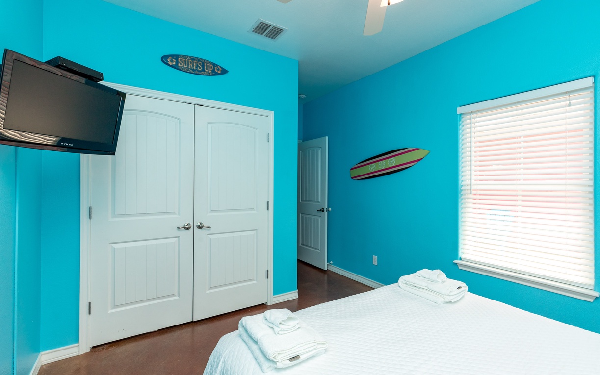 Dive into tropical dreams in your surf-themed bedroom with vibrant turquoise walls and cozy bedding.