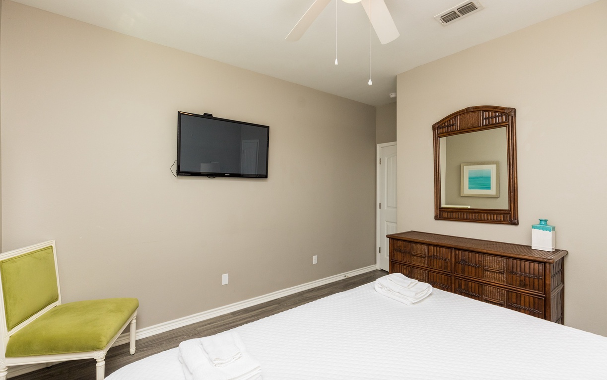 Relax in your peaceful bedroom with crisp linens, tropical-style furniture, and entertainment ready on the wall-mounted TV.