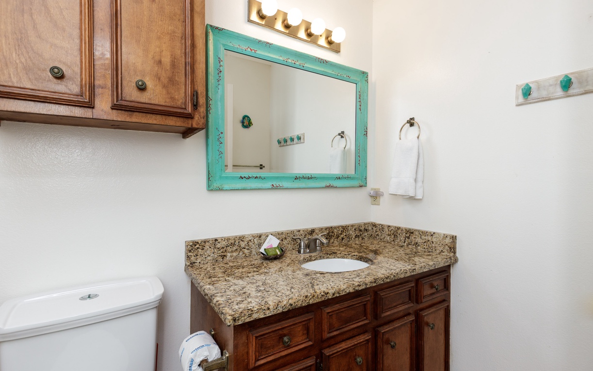 Freshen up in your charming bathroom featuring granite counters, custom cabinetry, and a distinctive turquoise mirror that adds coastal flair.