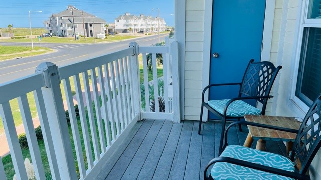Relax in your private balcony space with comfortable seating while enjoying peaceful residential views.
