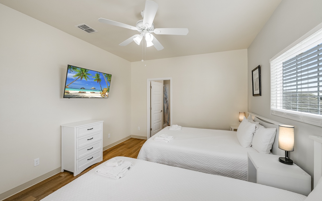 Relax in your bright twin bedroom with soft linens, tropical art, and gentle ceiling fan breeze.