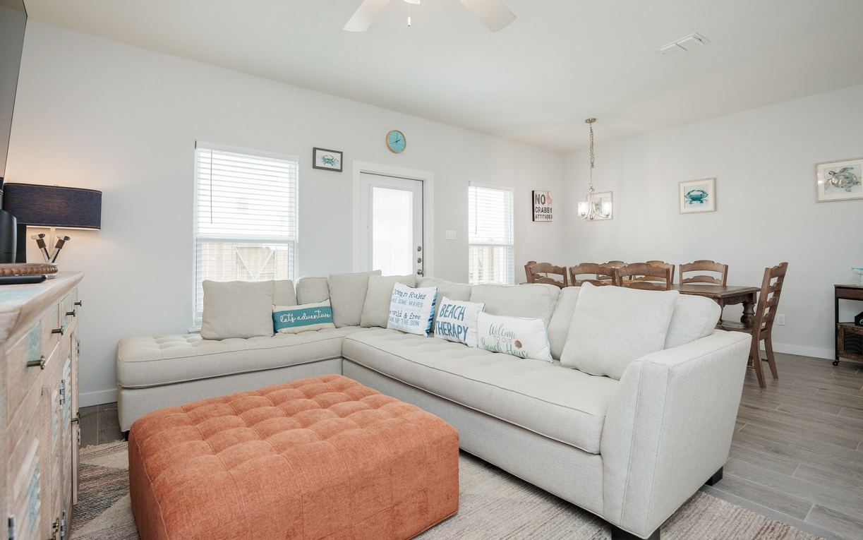 Unwind on your spacious sectional sofa with coastal-themed pillows, where the open layout flows seamlessly into your dining space for memorable meals together.