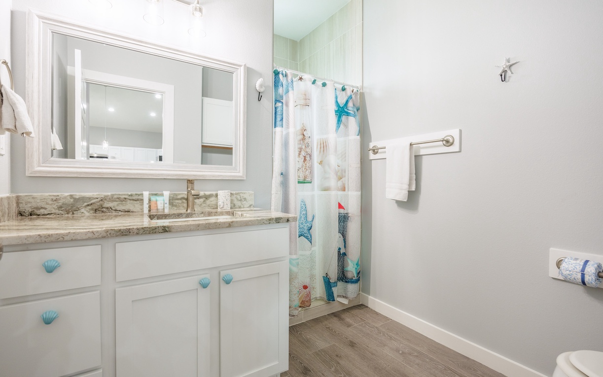 Your coastal-themed bathroom features granite countertops, seashell accents, and a charming nautical shower curtain that brings seaside vibes to your daily routine.