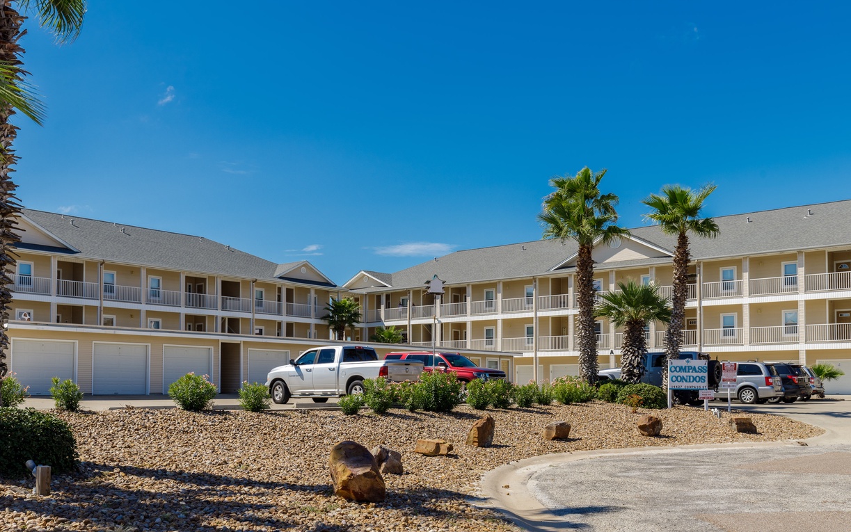Bright yellow resort buildings with palm trees create a cheerful coastal atmosphere under stunning blue skies.