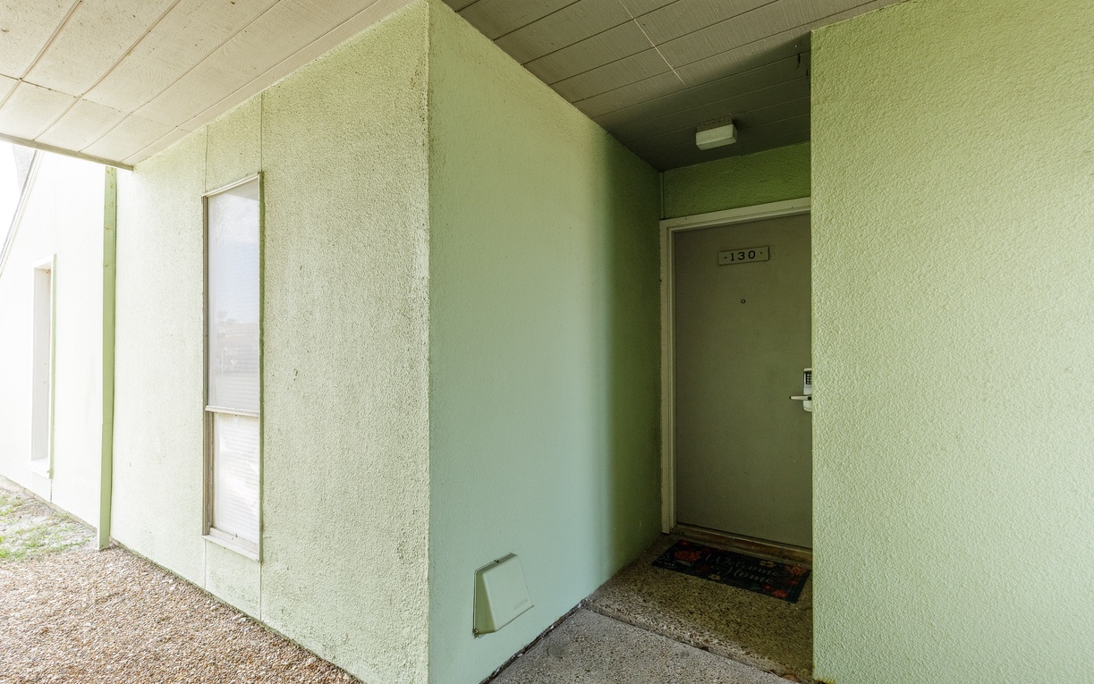 Property entrance with mint green exterior walls and covered walkway leading to unit 130.