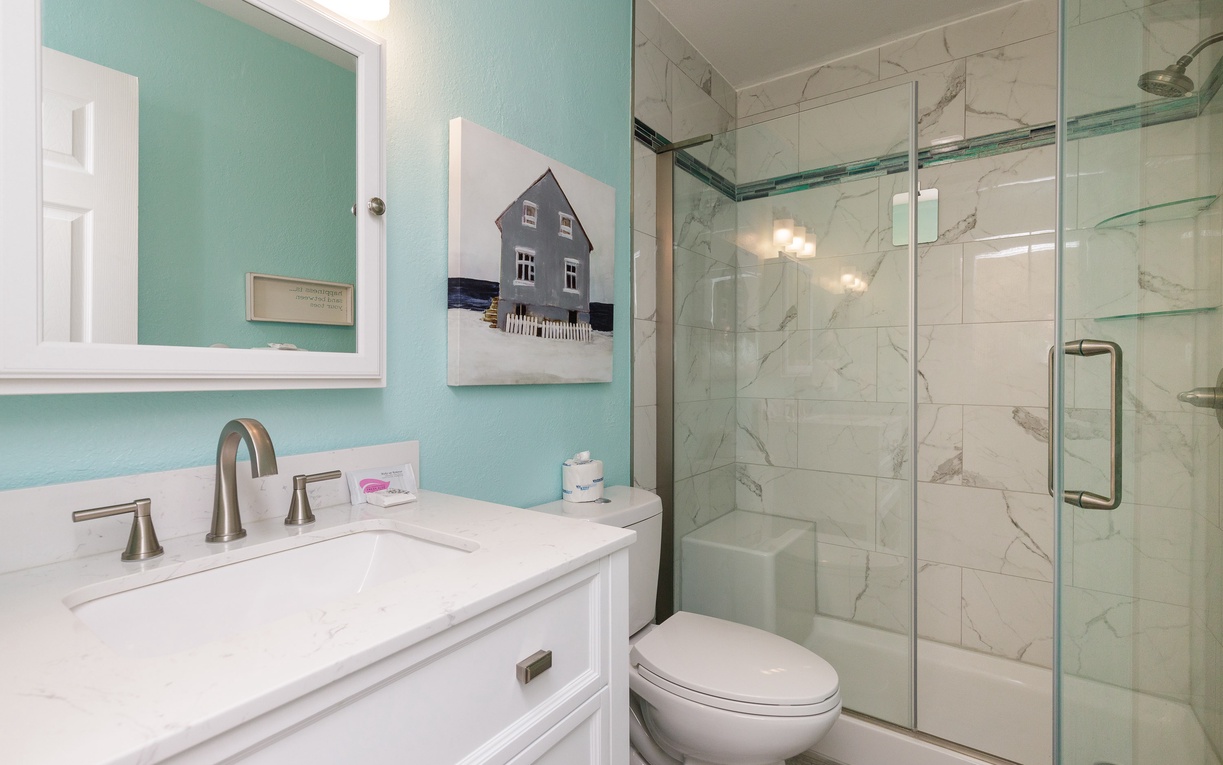 Step into your spa-like bathroom with calming mint walls, marble shower, and thoughtful coastal touches that make every morning feel refreshing.