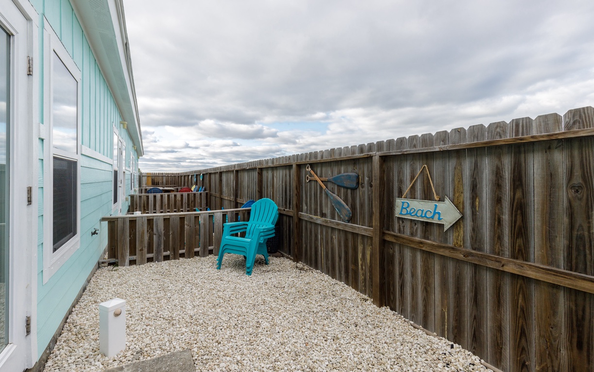 Step into your private coastal courtyard, where turquoise chairs await under open skies and beachy vibes surround you.