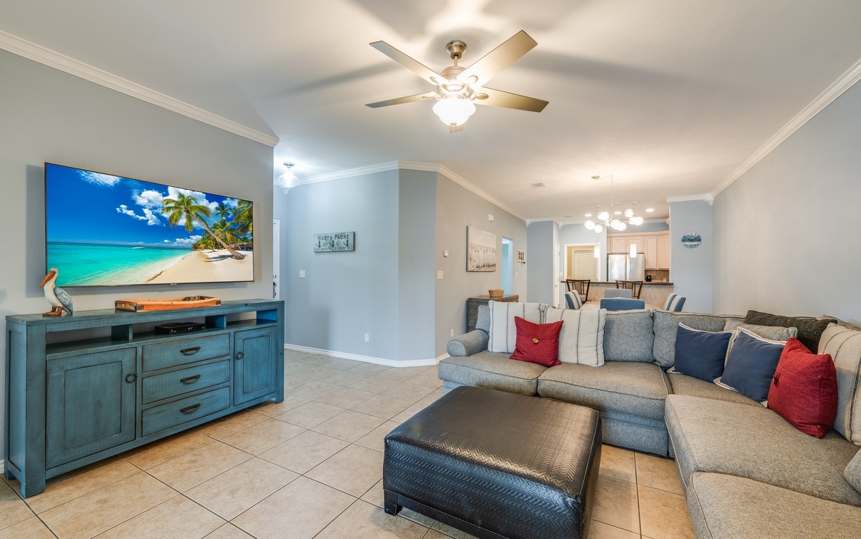 Relax in this spacious living room featuring a large TV and comfortable sectional sofa with colorful accent pillows for your ultimate comfort.